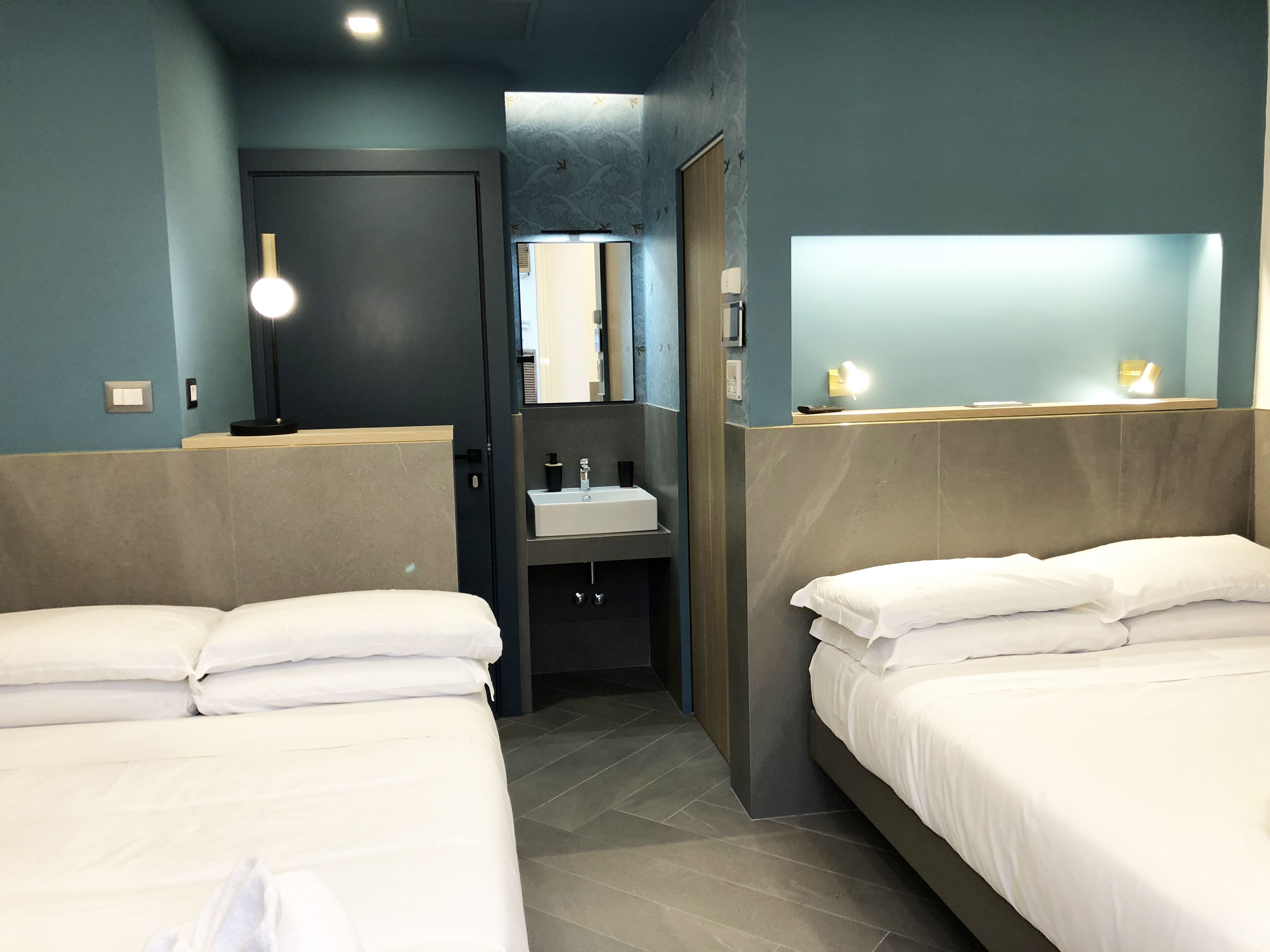 A hotel room with two beds, a bathroom, and a small sitting area.