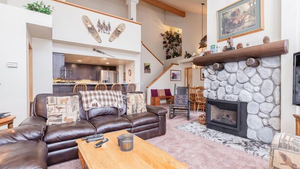 A spacious living area with a leather sofa, a wooden coffee table, and a stone fireplace. - Snowcreek #856, Updated 2 Bedrm + Loft Townhme in Snowcreek Phase 5 (Mammoth Lakes)