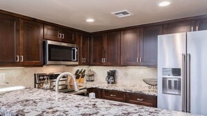 A modern kitchen with dark wood cabinets, stainless steel appliances, and a marble countertop. - Snowcreek #856, Updated 2 Bedrm + Loft Townhme in Snowcreek Phase 5 (Mammoth Lakes)