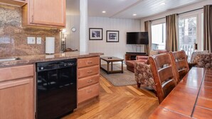 A modern kitchen with wooden cabinets, a dishwasher, and a dining area with a wooden table and chairs. - Sierra Park Villas #66, Updated 1 bedroom + 2 lofts / 2 bath, sleeps 6, free town shuttle stop! (Mammoth Lakes)