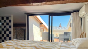 Una camera da letto con un letto grande, una parete a scacchi, una porta scorrevole in vetro per un balcone e vista su un edificio con una torre.