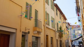 Una stretta via fiancheggiata da edifici con persiane verdi e un tetto in tegole.