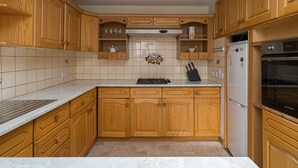 A kitchen with wooden cabinets, a stove, a refrigerator, and a microwave. - Spacious 3BR New Town Apartment (Edinburgh)