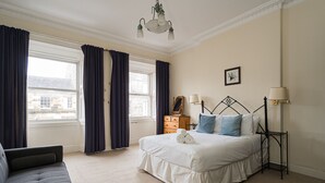 A neatly arranged bedroom with a large bed, a sofa, a dresser, and a nightstand. - Spacious 3BR New Town Apartment (Edinburgh)