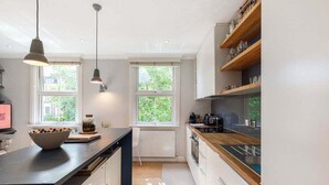 Uma cozinha moderna com ilha central, luminárias pendentes e prateleiras de madeira.