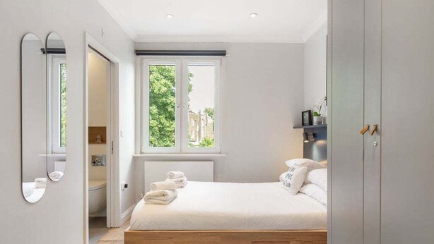 Quarto com cama, espelho grande, janela e armário.