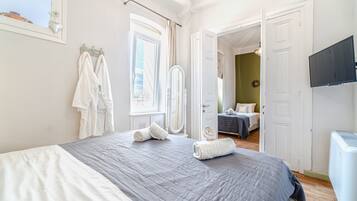 Un dormitorio con cama, espejo y televisión.