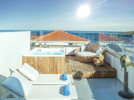 Una terraza en la azotea con jacuzzi, sillones de descanso y vistas al mar.