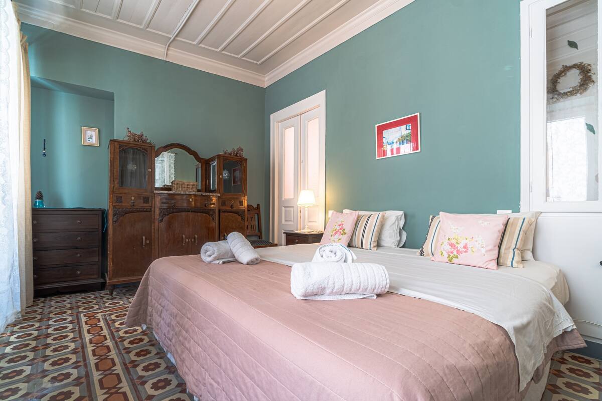 A bedroom with a bed, dresser, mirror, and patterned floor.