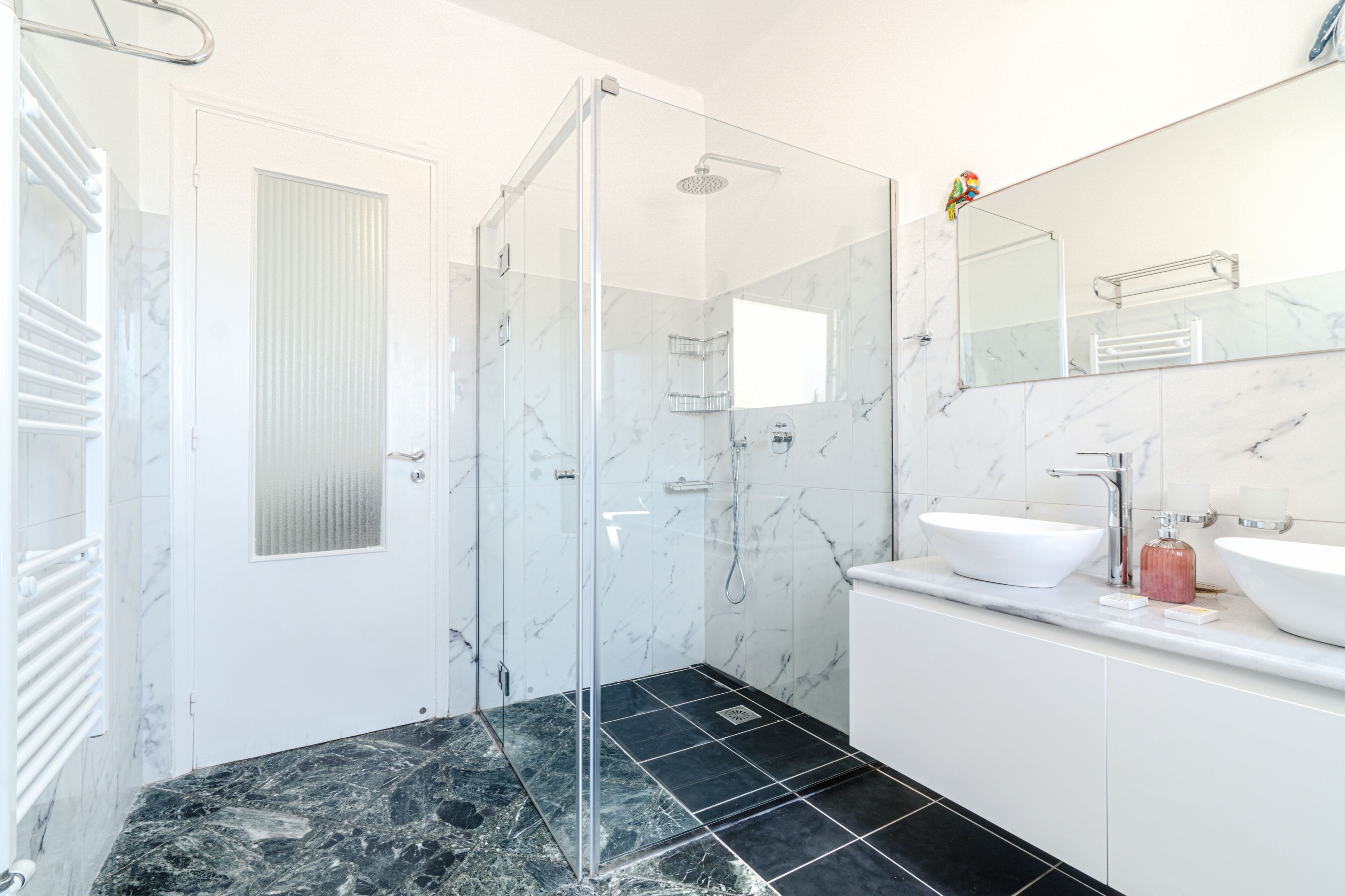A modern bathroom with a glass-enclosed shower, a white sink, and a large mirror.
