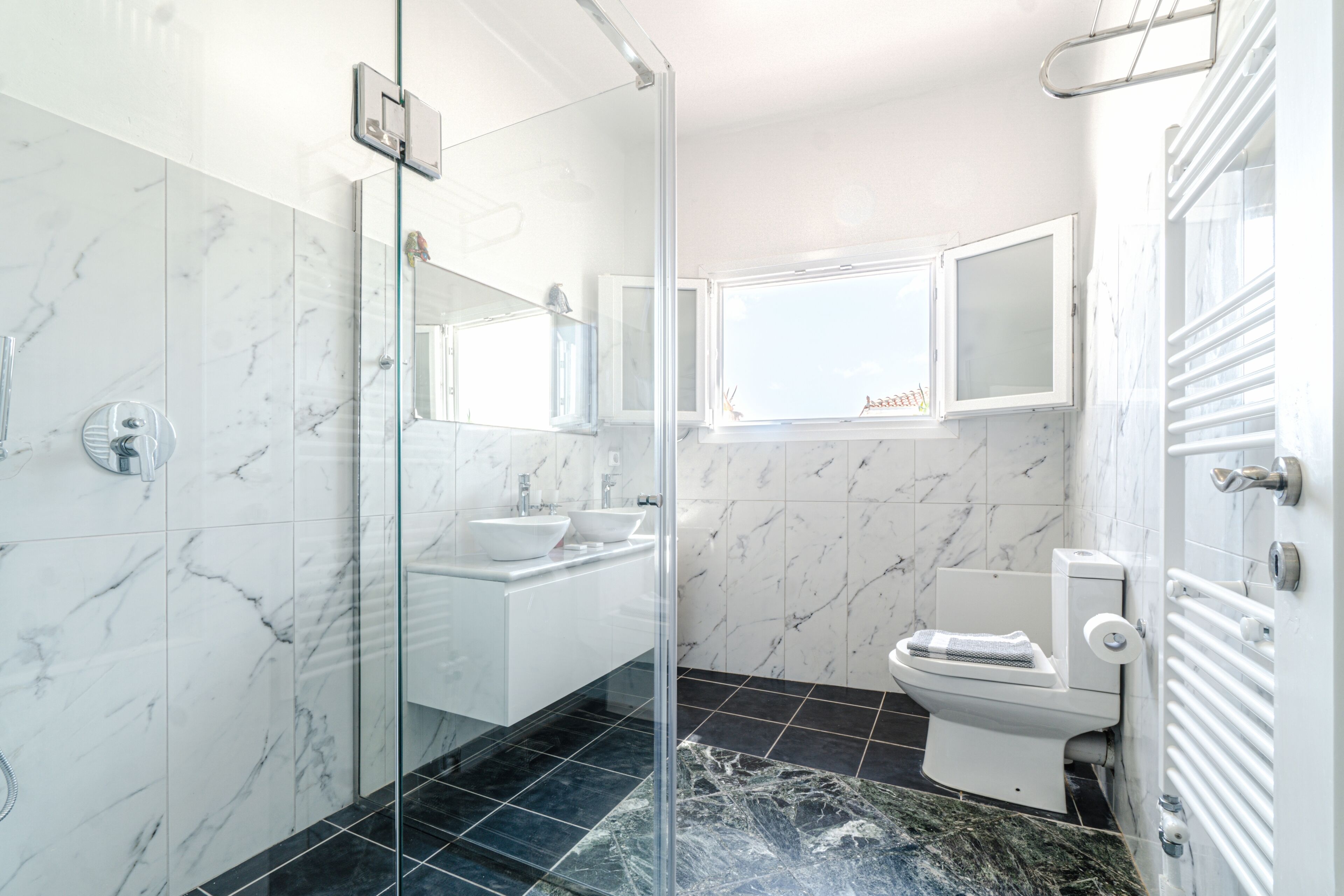 A modern bathroom with a glass shower enclosure, a white sink, and a toilet.