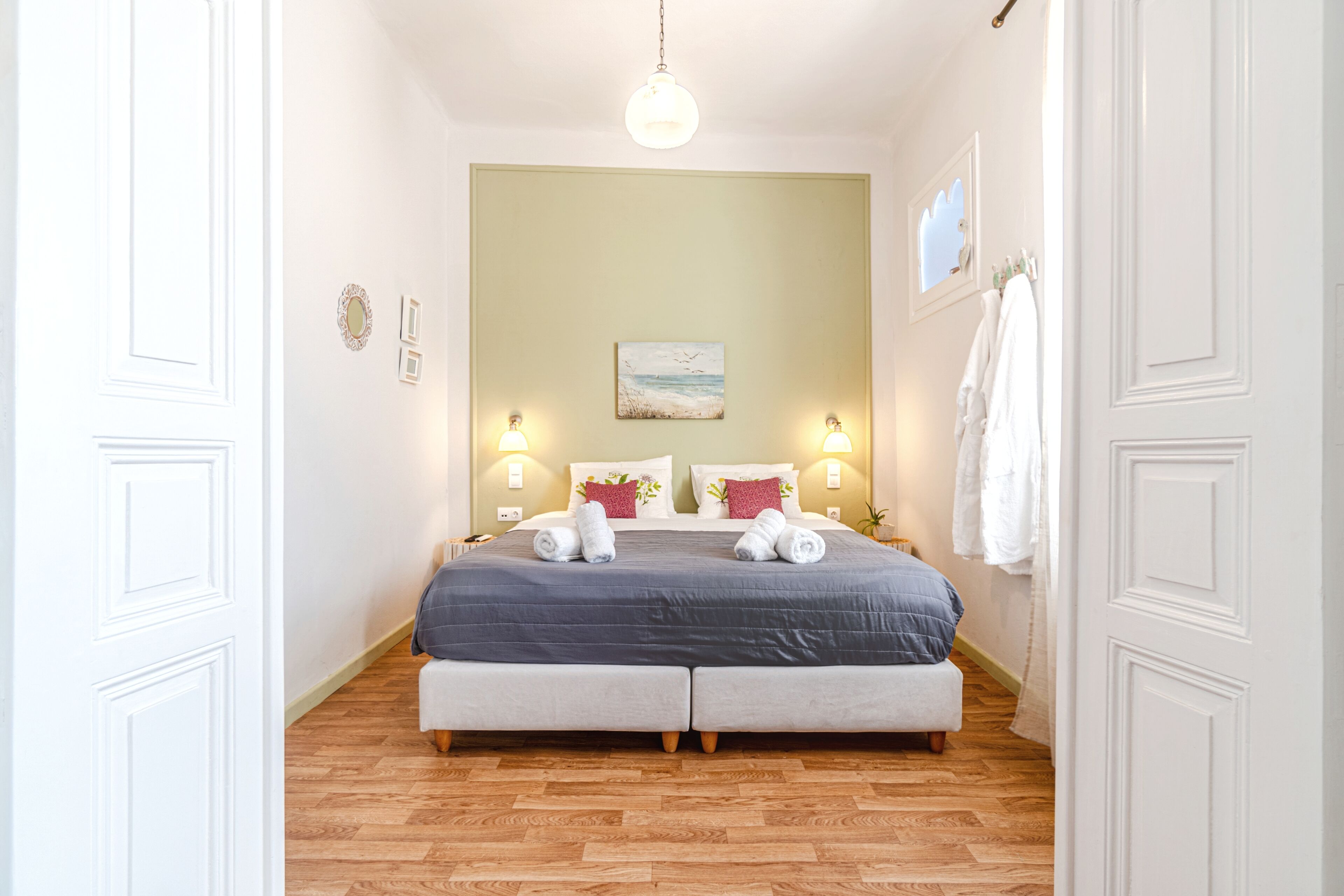 Un dormitorio con una cama, dos lámparas de noche, un cuadro y un perchero para toallas.