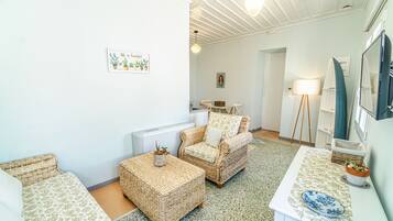 Un salón acogedor con muebles de mimbre, una pequeña mesa con un cuenco decorativo y una obra de arte enmarcada en la pared.