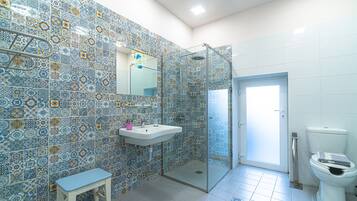 A bathroom with patterned tiles, a glass shower enclosure, a sink, and a toilet.