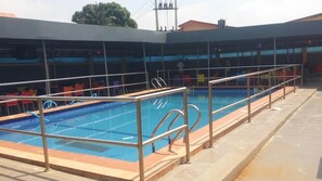 A swimming pool with a metal railing, surrounded by a covered seating area with tables and chairs. - Demeg Hotel And Suites (Lagos)