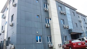 A multi-story hotel building with the name "DEMEG HOTEL & SUITES" on the facade. It features air conditioning units on the exterior walls and windows. - Demeg Hotel And Suites (Lagos)