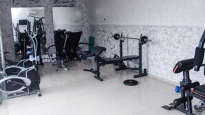 A gym with various exercise equipment, including a bench press, a squat rack, and free weights. - Demeg Hotel And Suites (Lagos)