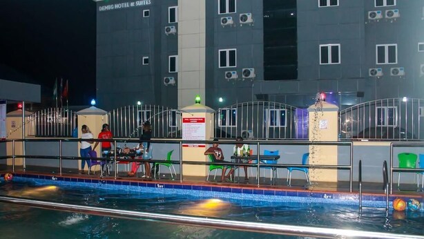 A hotel with a swimming pool, outdoor seating, and a well-lit facade. - Demeg Hotel And Suites (Lagos)