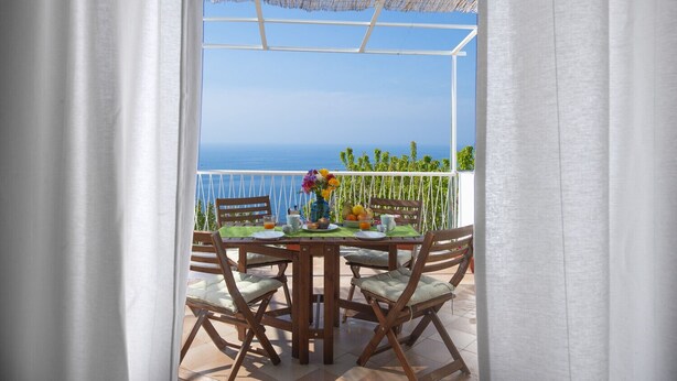 A balcony with a table set for breakfast, overlooking the sea. - La Casa di Nonno Mario (Praiano)