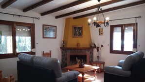 Ein Wohnzimmer mit Kamin, zwei Sofas, einem Holztisch und einer Chandelüster.