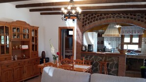Ein gemütliches Wohnzimmer mit einer Couch, Holzkredänzen und einer Küchenzeile mit Backsteinwand und gefliestem Fliesenspiegel.