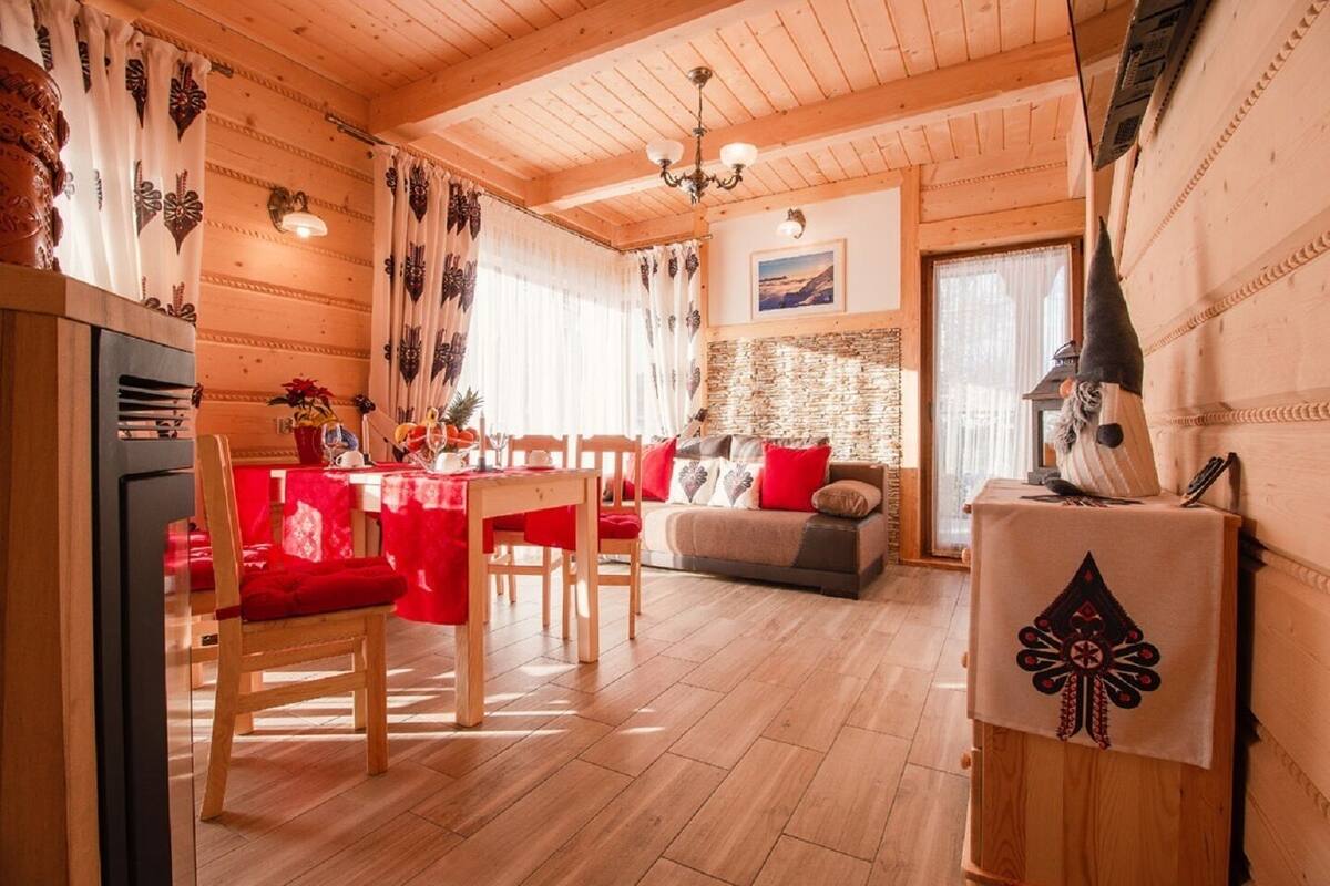 A cozy wooden interior with a dining area, sofa, and a fireplace.