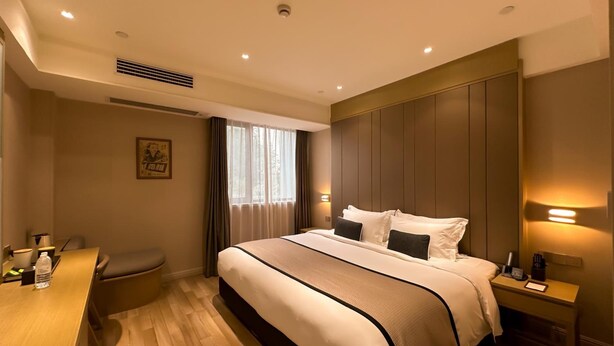 A hotel room with a large bed, bedside tables, a desk, and a window with curtains. - Shanghai Deco Hotel (SHANGHAI)
