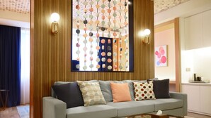A modern living room with a grey sofa, patterned cushions, a glass coffee table, and a decorative wall hanging. - Shanghai Deco Hotel (SHANGHAI)