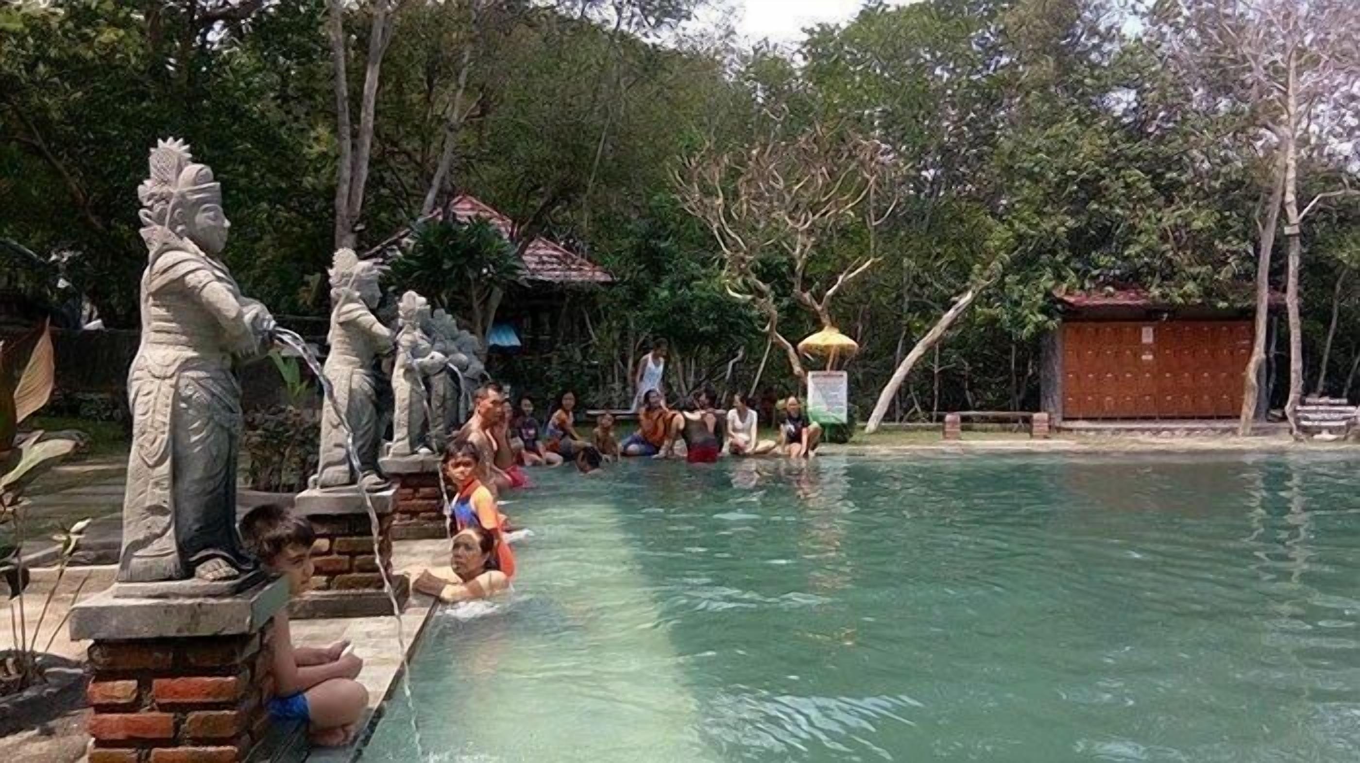 Una piscina con estatuas y gente alrededor.