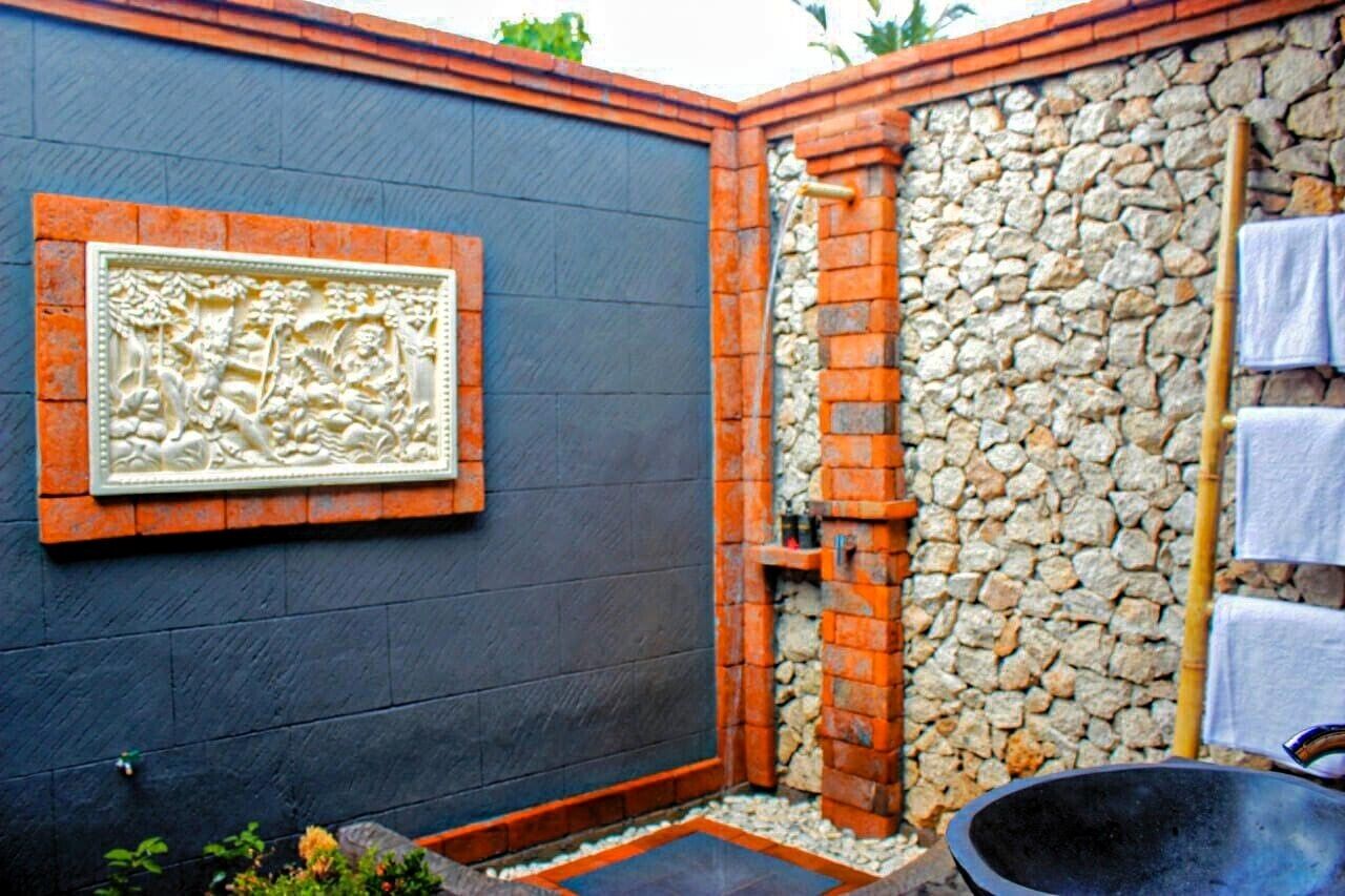 A spa area with a stone wall, a black wall with a decorative relief, and a black tub.