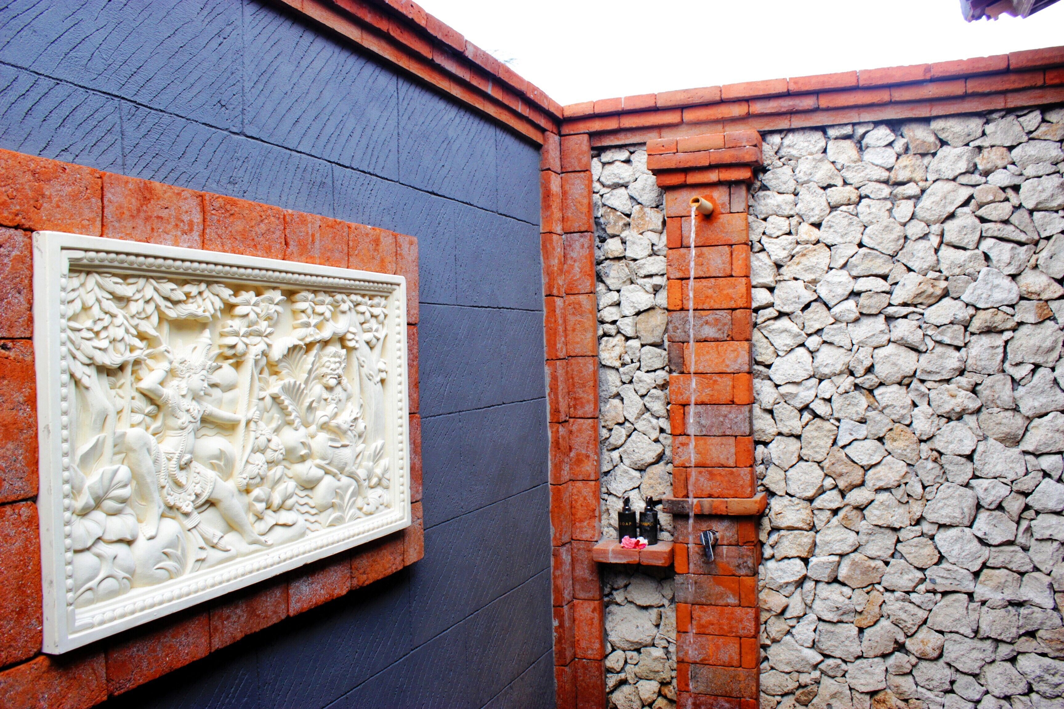 A wall with a decorative relief and a stone wall with a small shelf.