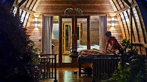 A wooden cabin with a porch, a bed, and a dog. - Umma Bali Menjangan (Pejarakan)