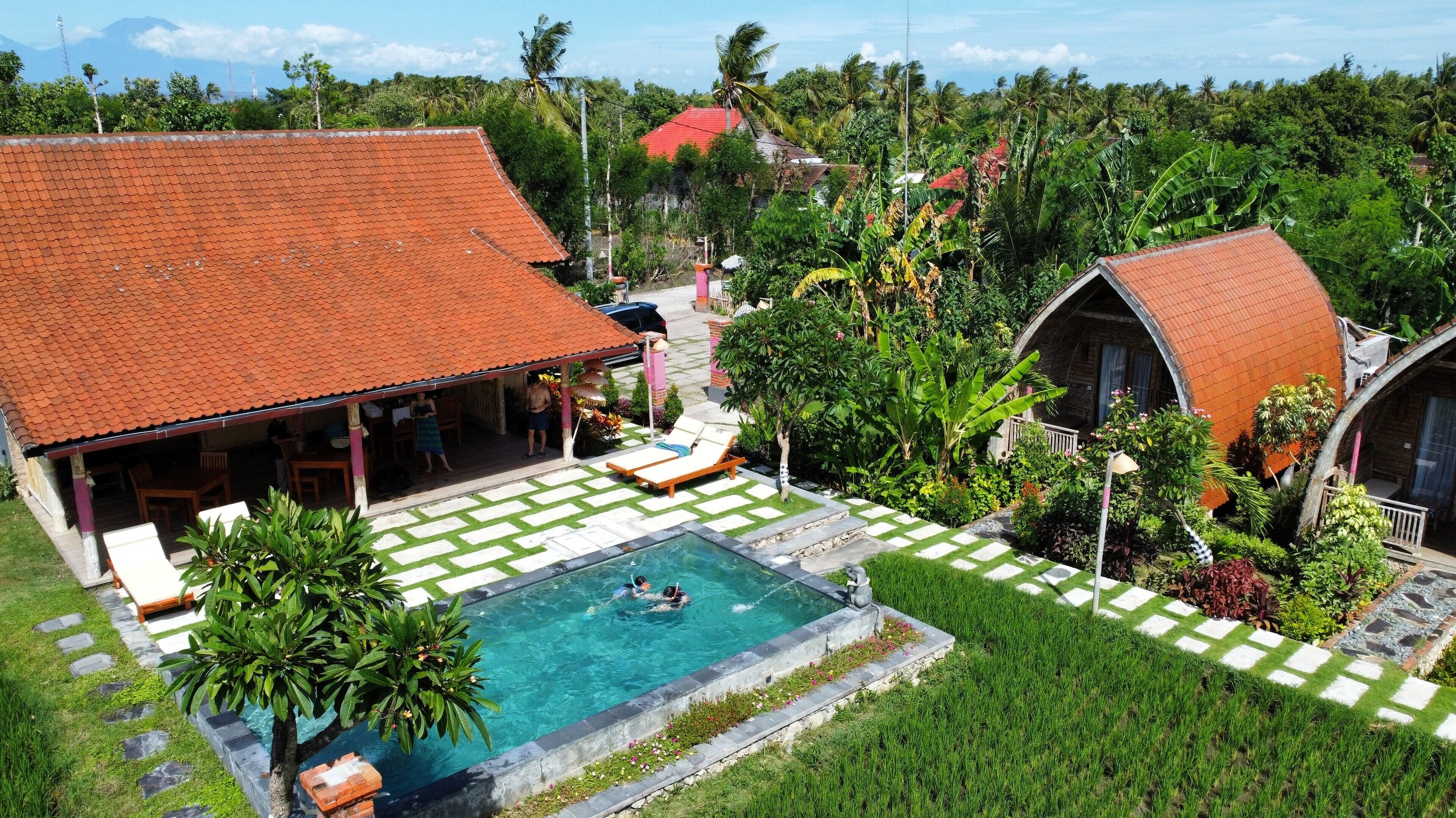 A resort with a swimming pool, lounge chairs, and a red-roofed building.