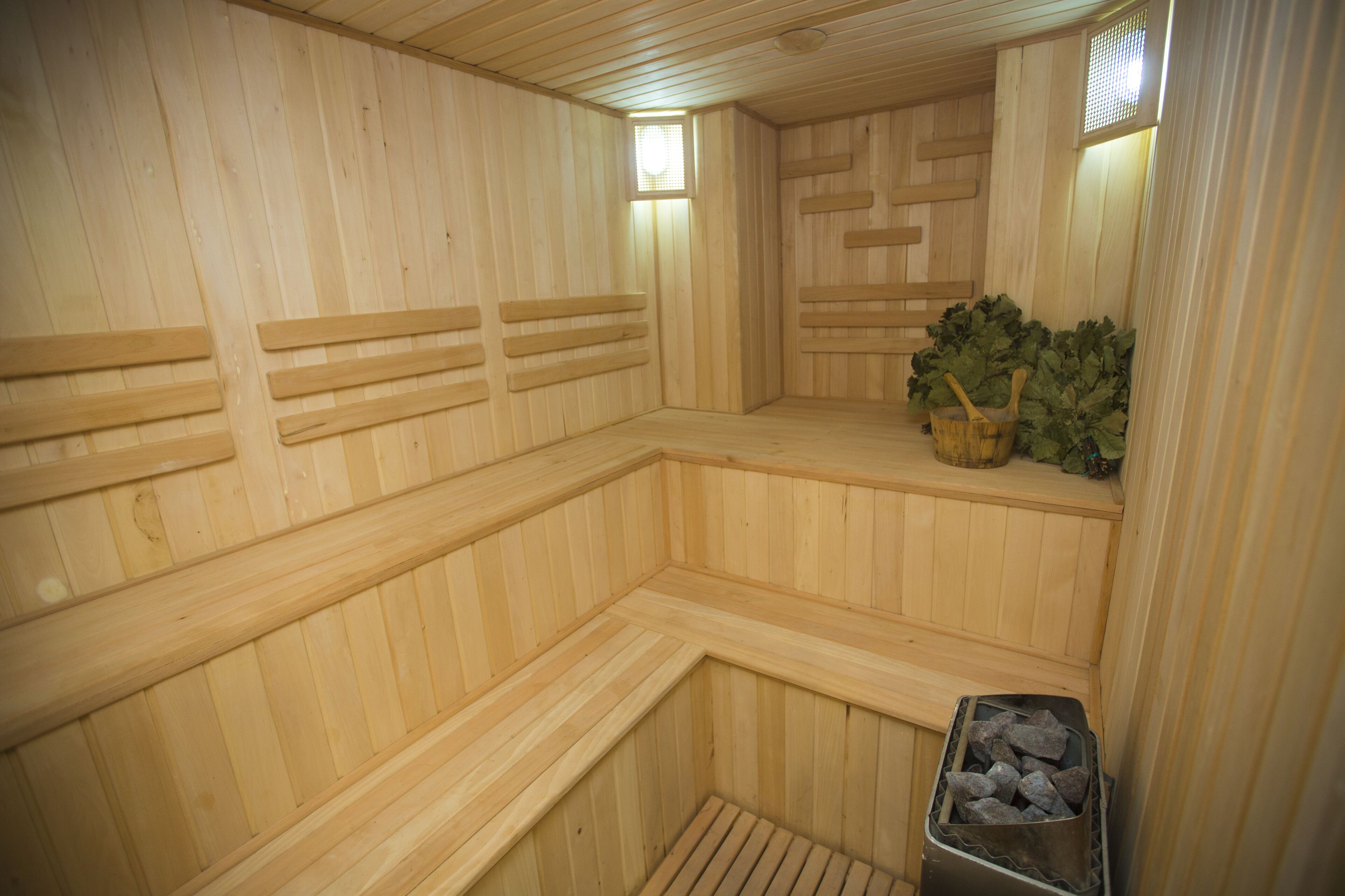 A sauna with wooden benches and a small trash bin.