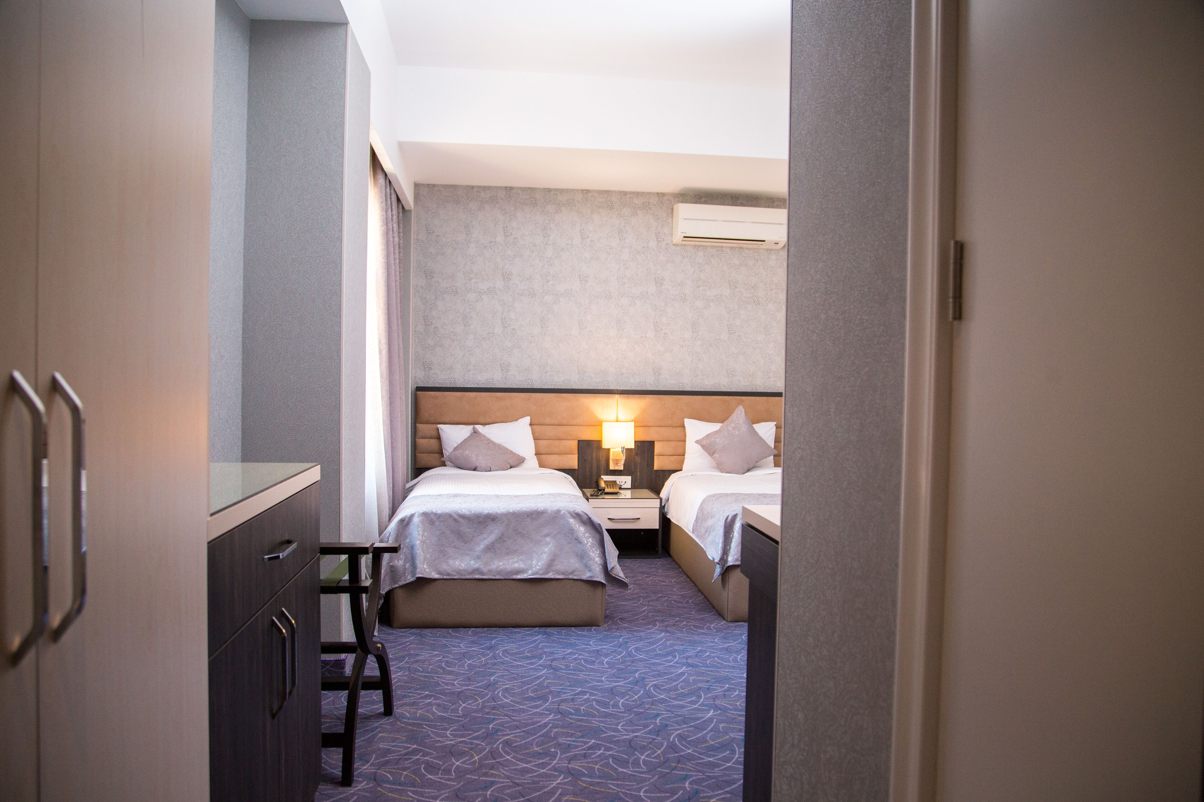 A hotel room with two beds, a desk, and a wardrobe.
