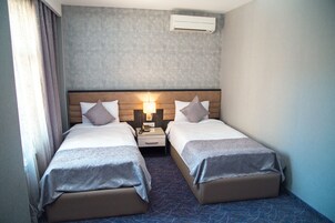 Een hotelkamer met twee bedden, een nachtkastje, een lamp en een airconditioning.