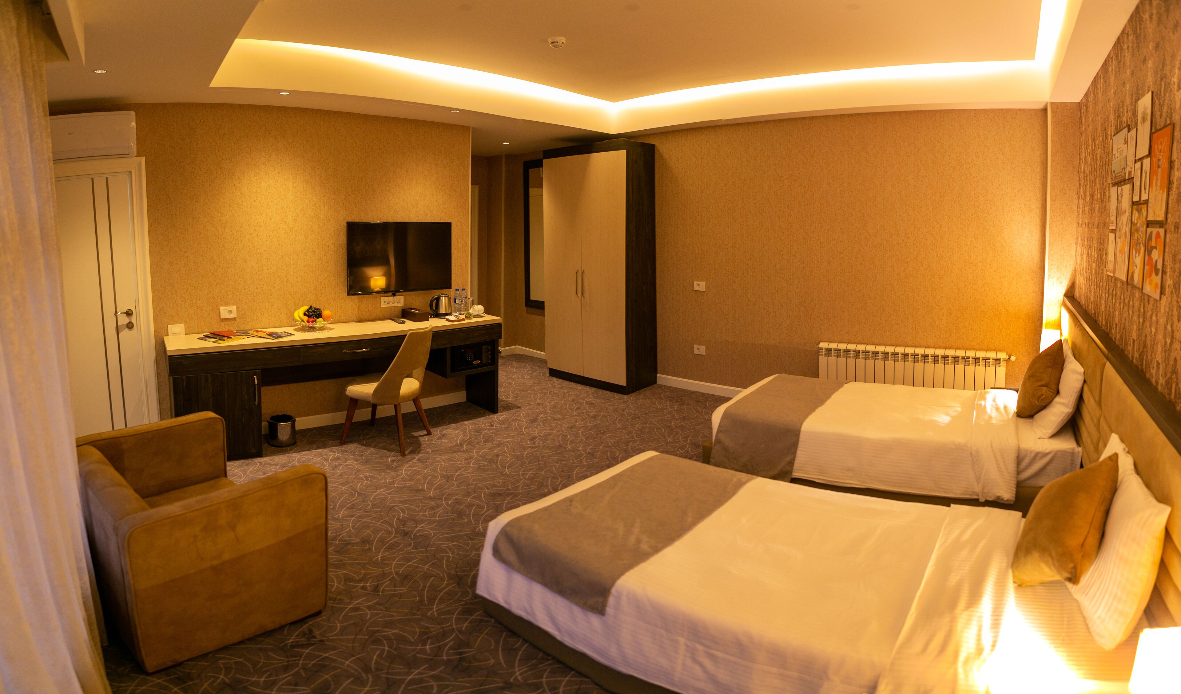 A hotel room with two beds, a desk, a chair, a TV, and a wardrobe.