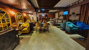 Un espace de détente moderne, doté de différents types de sièges, d’un bar et d’un écran de télévision.