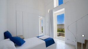 Una habitación de hotel moderna con una cama grande, un balcón con vistas y una escalera.