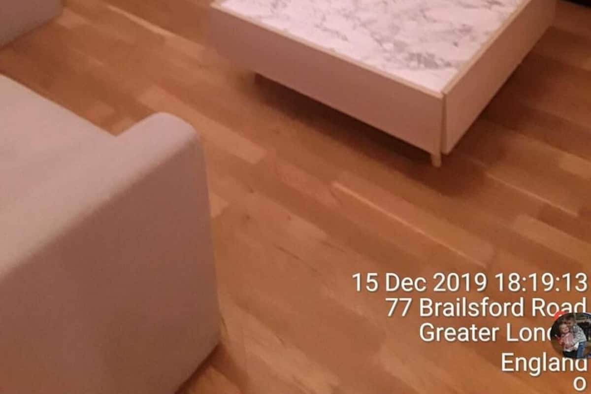 Ein Wohnzimmer mit Holzboden, einem weißen Sofa, einem dunklen Sessel und einem kleinen Tisch mit Marmorplatte.
