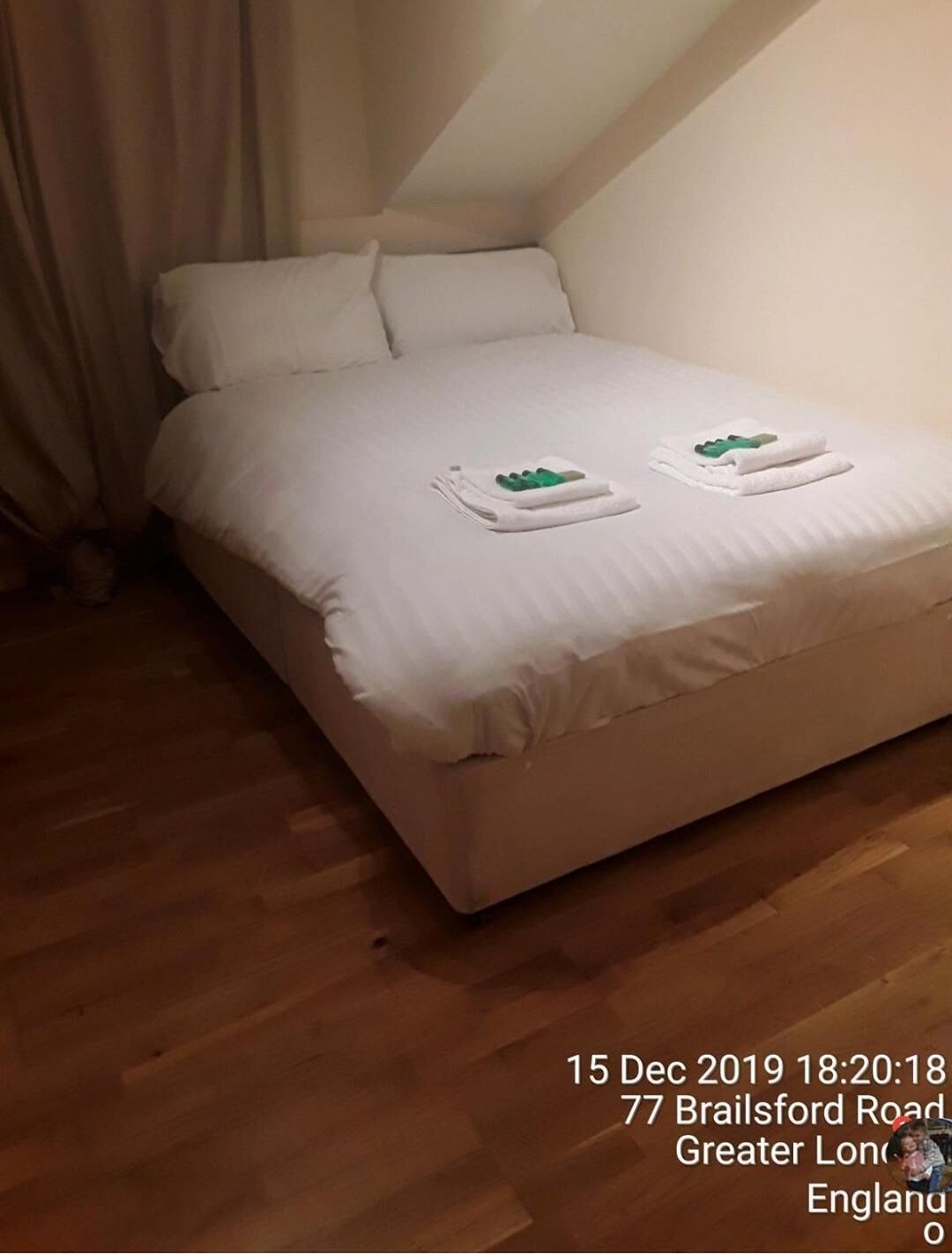 Un lit bien fait, avec des draps blancs et deux serviettes pliées posées sur le dessus.