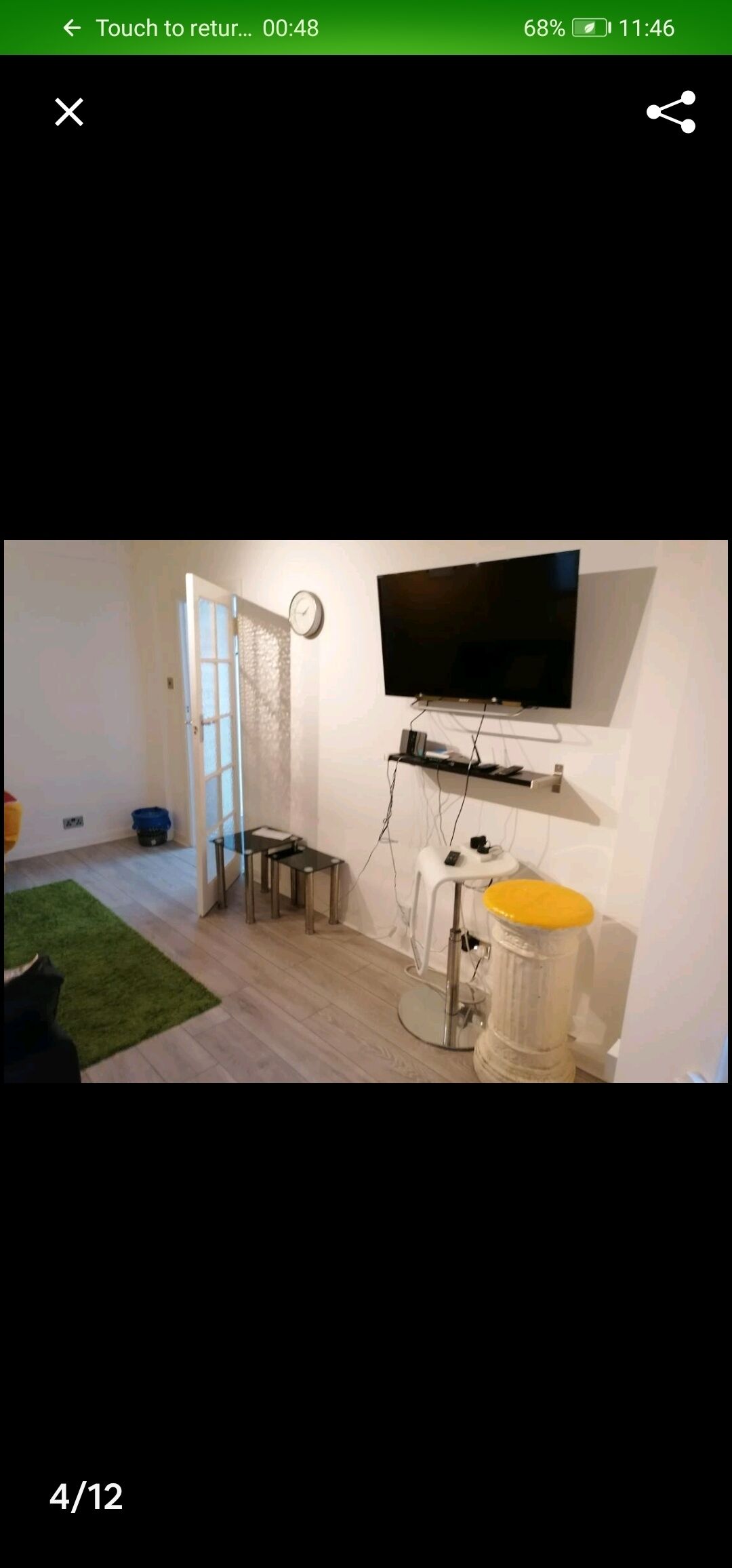 A room with a flat-screen TV mounted on the wall, a small table, and a chair.