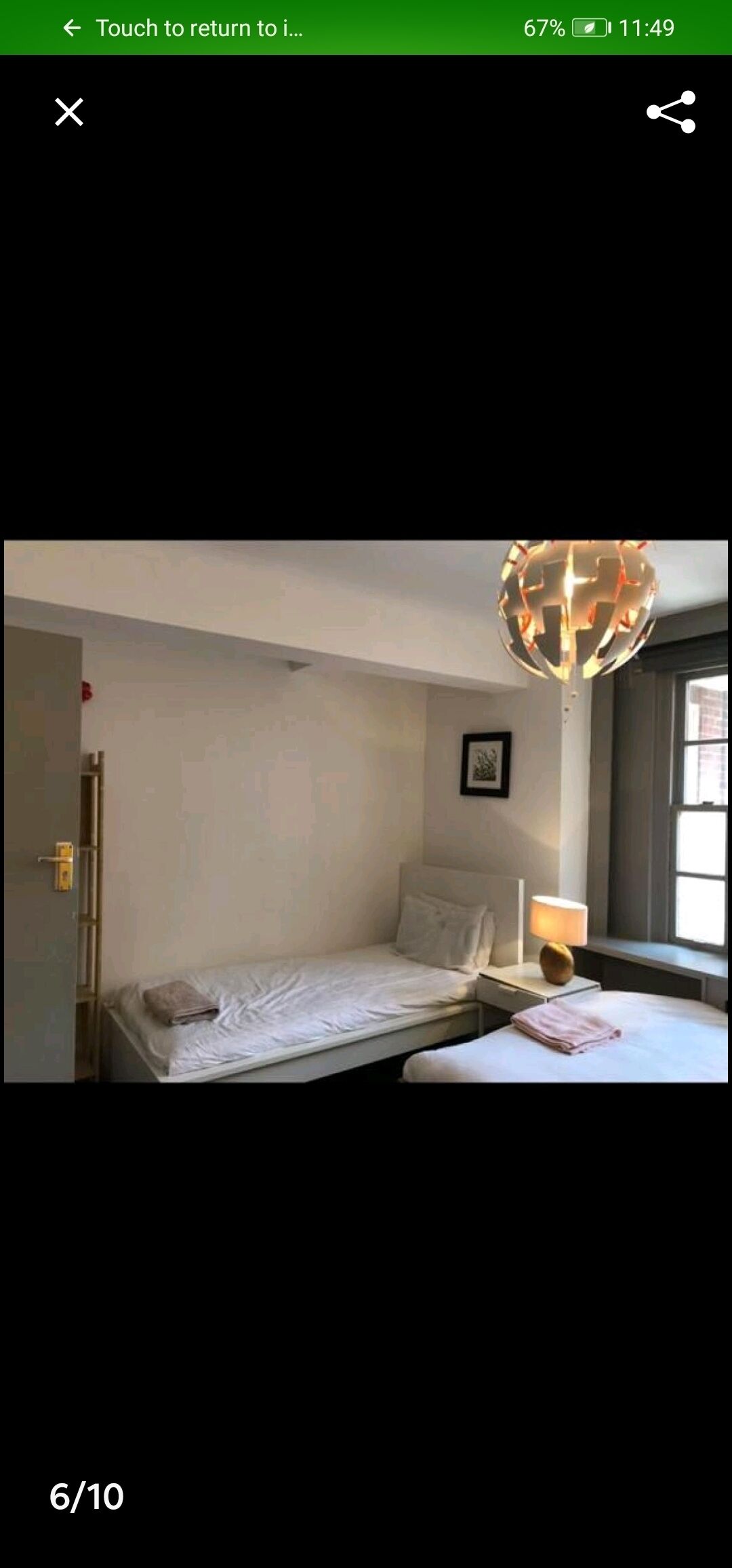 A small, single-bed room with a bedside table, a lamp, and a globe hanging from the ceiling.