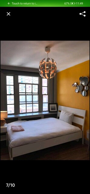 A bedroom with a bed, a unique spherical lamp, a window, and a wall-mounted mirror.