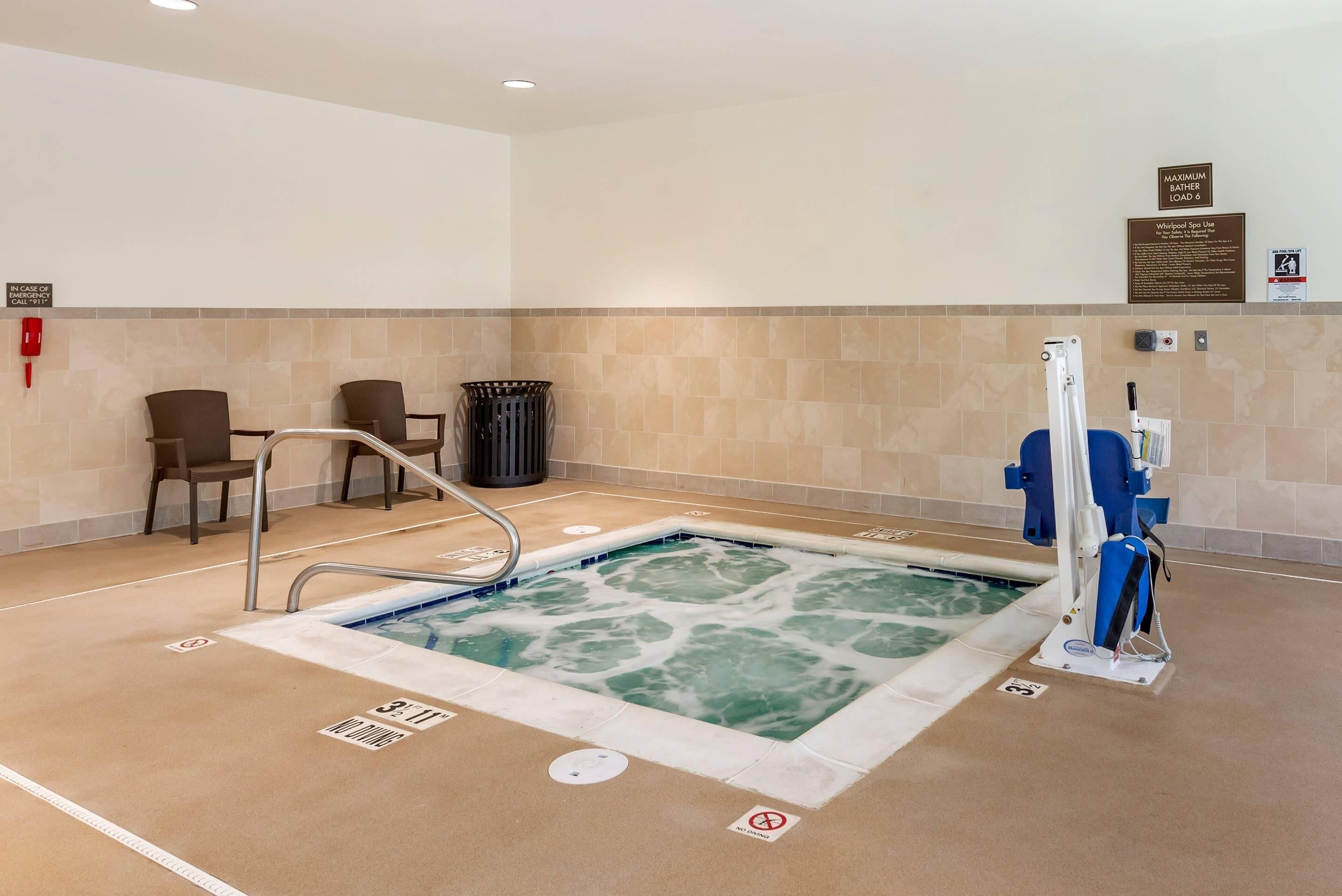 A pool area with a hot tub, lounge chairs, and a no diving sign.