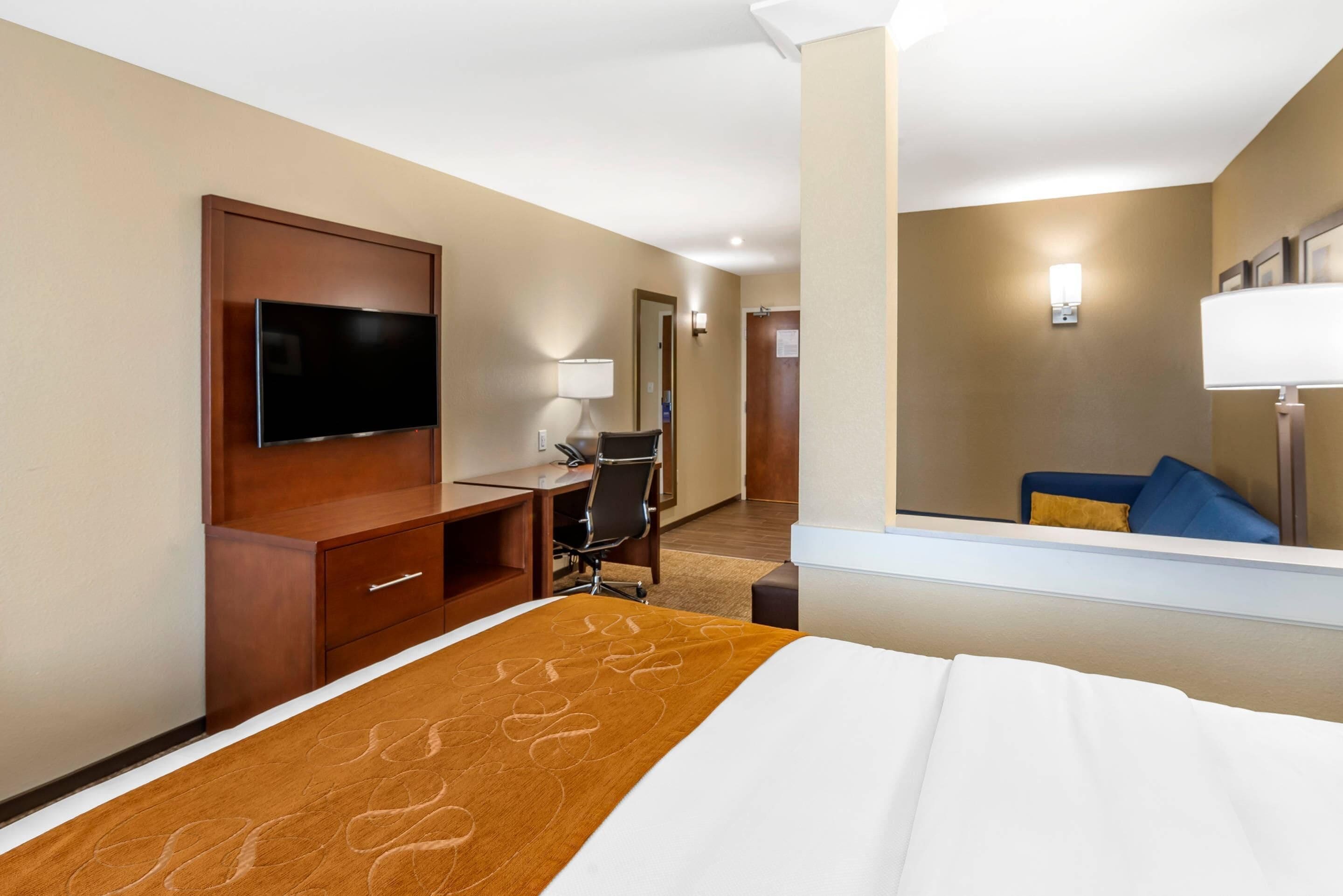 Une chambre d’hôtel équipée d’un lit, d’un bureau, d’une chaise, d’une télévision et d’un miroir.