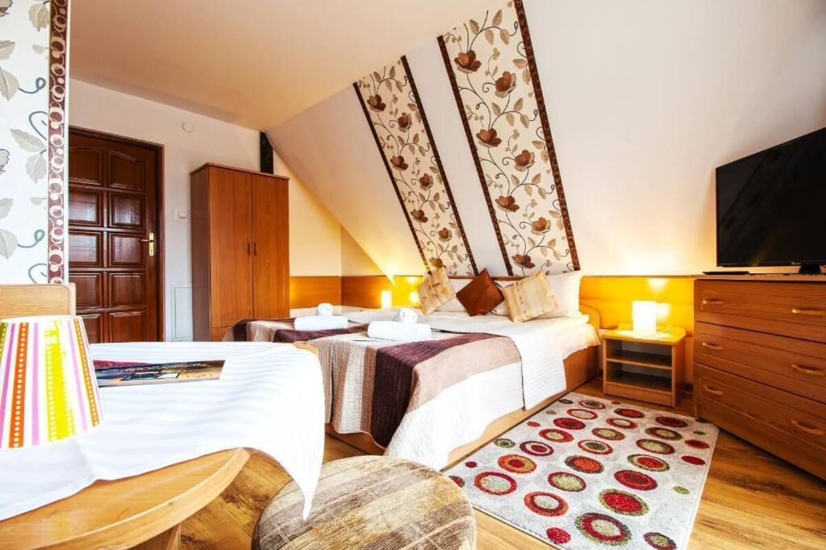 A hotel room with two beds, a wardrobe, a television, and a decorative wall panel.