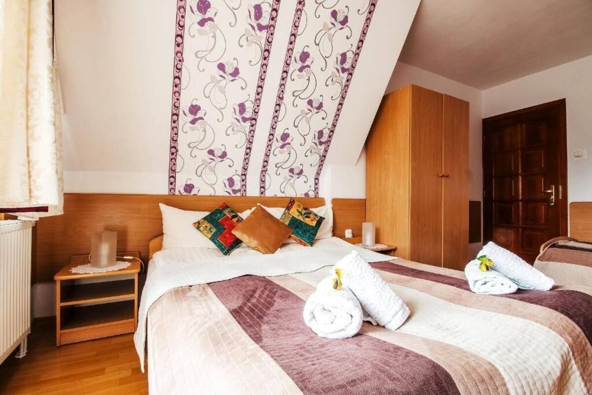 A hotel room with a large bed, wooden headboard, and a wooden wardrobe.