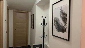 A hallway with a wooden door, a coat rack, and a framed picture on the wall. - Victory House 3 (Celano)