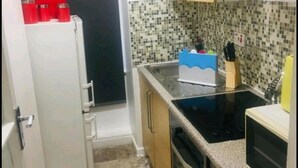 A compact kitchen with a refrigerator, a microwave, and a stove. - Forset Court (London)
